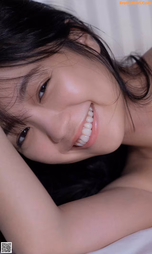 A woman laying on top of a bed smiling.