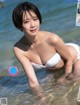 A woman in a white bikini is standing in the water.