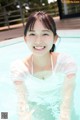 A woman in a white shirt is smiling in a pool.