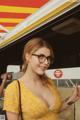 A woman wearing glasses standing in front of a food truck.