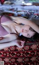 A woman laying on top of a rug on a bed.