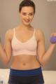 A woman in a pink bra top and blue shorts holding two purple dumbbells.