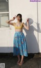 A woman standing in front of a white wall with her hands up.