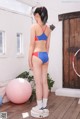 A woman in a blue and red bikini standing next to a pink ball.