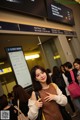 A woman standing in front of a large screen at an airport.