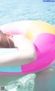 A woman in a bikini laying on an inflatable beach ball.