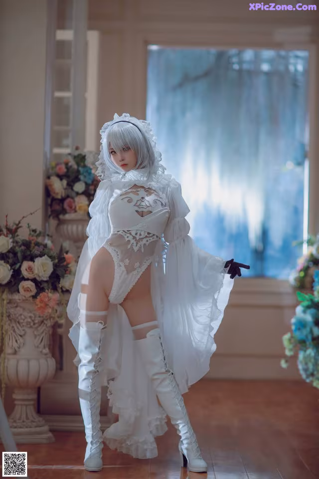A woman in a white dress and thigh high boots posing for a picture.