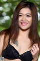 A woman in a black bra with a tattoo on her chest.