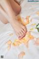 A woman's feet on a bed covered in rose petals.