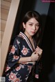 A woman in a kimono leaning against a wall.